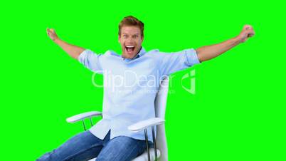 Man sitting on swivel chair with raised arms to show his success on green screen