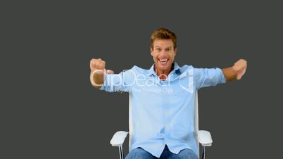 Man on swivel chair giving thumbs up on grey screen