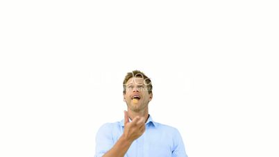 Man catching an orange segment with his mouth on white screen