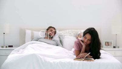 Woman reading a book while partner is sleeping