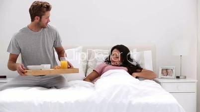 Handsome man bringing his partner breakfast in bed