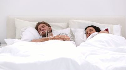 Couple sleeping peacfully with partner pressing snooze