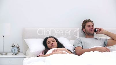 Man talking on phone while his partner is sleeping