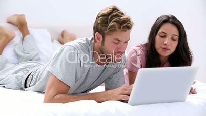 Couple using the laptop lying bed