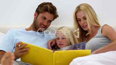 Parents and daughter reading book together