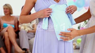 Pregnant woman receiving blue baby gro from her friend