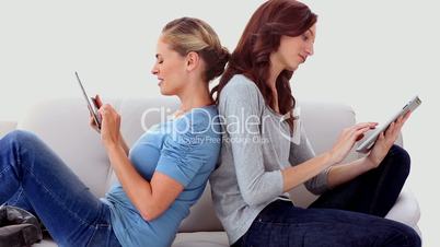Friends sitting back to back using tablet pc