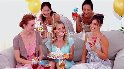 Woman blowing out the birthday candles surrounded by her friends