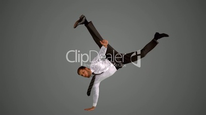 Businessman doing one hand handstand on grey background