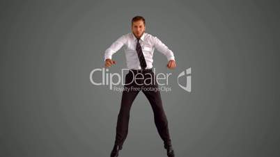 Businessman jumping and doing the splits on grey background