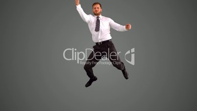 Businessman jumping and punching air on grey background
