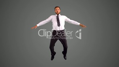 Businessman jumping and stretching towards the camera on grey background