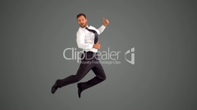 Businessman jumping and giving thumbs up on grey background
