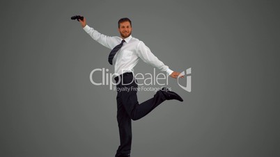 Businessman jumping and holding binoculars on grey background