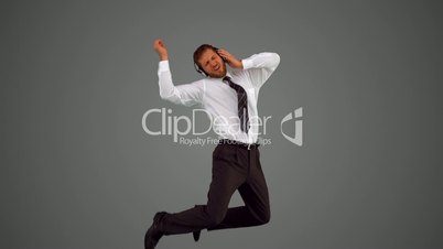 Businessman leaping and listening to music on grey background