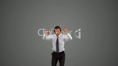 Businessman jumping and listening to music on headphones on grey background
