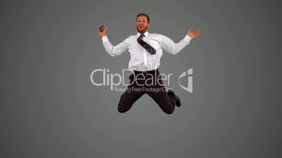 Businessman holding alarm clock jumping on grey background