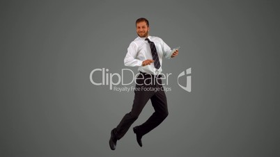 Businessman holding digital tablet jumping on grey backgroundjumping