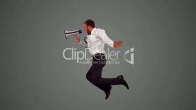 Businessman holding megaphone and jumping on grey background