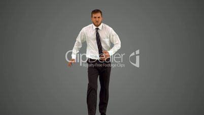 Businessman walking towards camera and dancing funnily on grey background