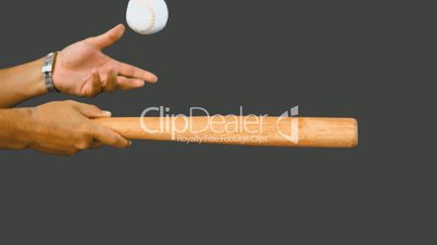 Man hitting baseball with wooden bat and keeping it up