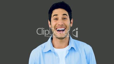 Man laughing at the camera on grey background