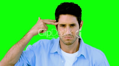 Man pretending to shoot himself with hand on green screen