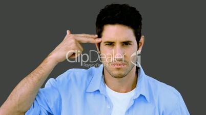 Man pretending to shoot himself with hand on grey background