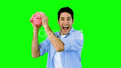 Man shaking piggy bank excitedly on green screen