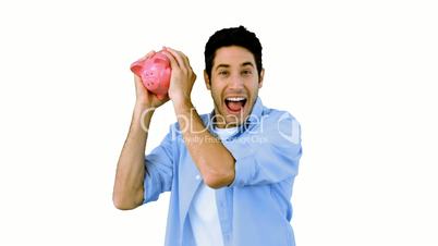 Man shaking piggy bank excitedly on white background