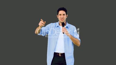 Man singing into microphone and dancing on grey background
