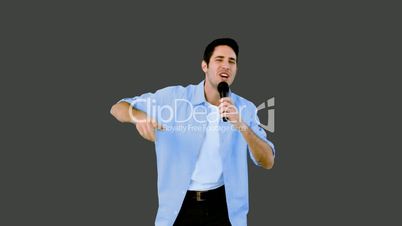 Man singing into microphone on grey background