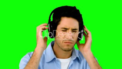 Man listening to music with headphones on green screen