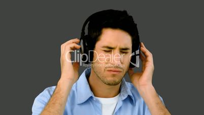 Man listening to music with headphones on grey background