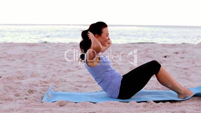 Woman doing sit ups on the beach