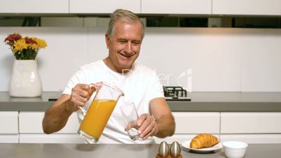 Retired man pouring orange juice for breakfast