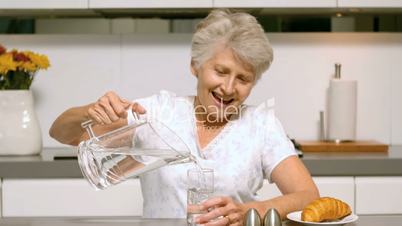 Elderly woman pouring a glass of water for breakfast