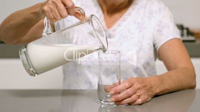 Woman pouring glass of milk in the kitchen