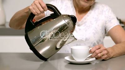 Woman pouring hot water from kettle into cup