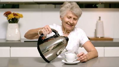 Retired woman pouring boiling water from kettle into cup