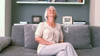 Retired woman laughing on the couch