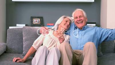 Retired couple sitting down on the couch and smiling