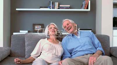 Retired couple flopping down on the couch