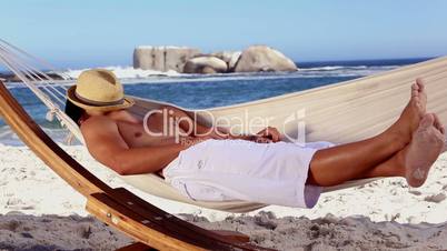 Man wearing straw hat relaxing in a hammock