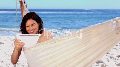 Smiling woman using tablet in a hammock