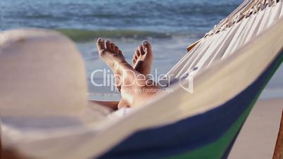 Woman relaxing on the beach in a hammock