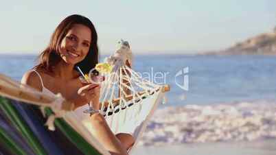 Cute woman holding a cocktail in a hammock