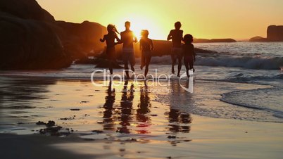 Silhouettes of friends running into the sea