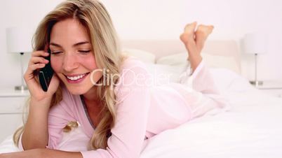 Blonde woman talking on phone in bedroom