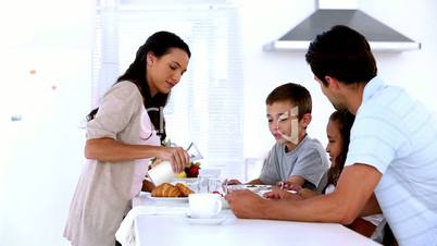 Mother pouring milk at family breakfast